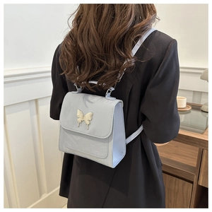 Gros plan d'un mini sac à dos bleu clair avec détail papillon argenté porté au dos