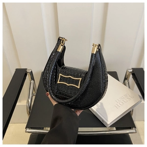 Detail view of black crocodile-embossed leather handbag with a gold rectangular metal buckle