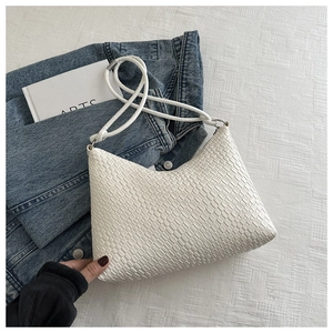 Detailed close-up of a white woven shoulder bag with elegant textures and thin straps