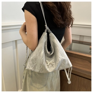 Détail du sac à bandoulière argenté métallisé froissé avec boucle décorative papillon