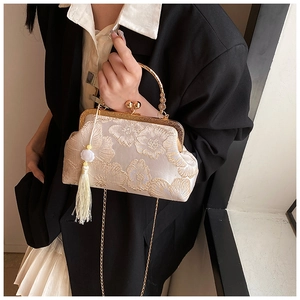 Detail of embroidered floral handbag with gold clasp, metal handle and bead tassel
