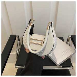 White croc-textured crescent handbag with gold buckle on a stylish leather chair