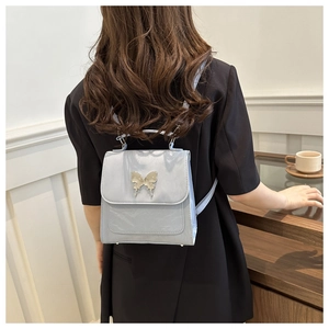 Detail of light blue glossy backpack with a silver butterfly metal buckle and carry handle