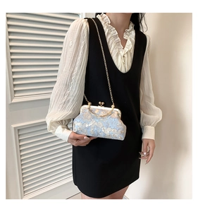 Detail of vintage blue jacquard silk clutch bag with gold kiss lock and chain