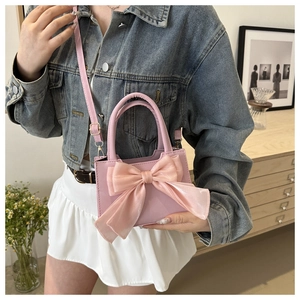 Detailed view of pink crossbody bag featuring a large decorative organza bow and top handle