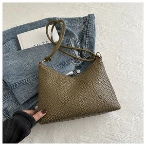 Detail of woven texture and slim shoulder strap on an olive green tote shoulder bag