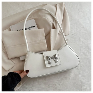 Close-up of white underarm bag with silver metal bow clasp on leather texture