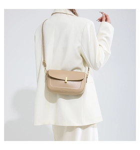 Detail view of khaki leather crossbody bag with golden buckle on a white blazer model