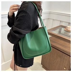 Gros plan d'un sac cabas en cuir vert herbe avec double surpiqûre élégante sur mannequin