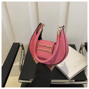 Macro detail of pink crocodile-embossed half-moon handbag with gold hardware accent