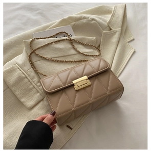 Detail of beige quilted shoulder bag with gold metal clasp and chain strap design