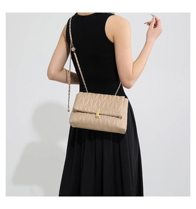 Detail of beige V-quilted shoulder bag with gold metal lock and chain strap