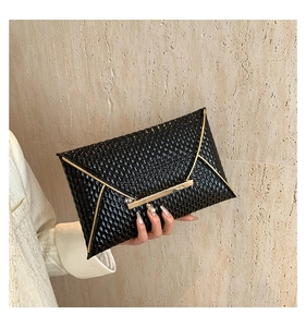 Detailed view of black patent leather envelope clutch with gold metal trim and textured finish