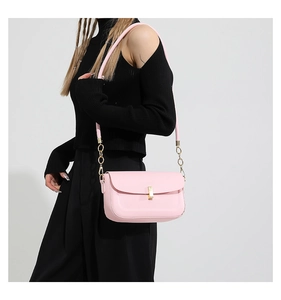 Close-up of pink leather crossbody bag with gold square buckle and chain strap on model
