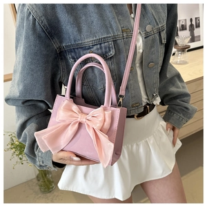 Mini borsa rosa a tracolla con grande fiocco decorativo indossata da una modella