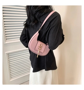 Pink crescent hobo bag with gold metal logo and tassel details shown on a model