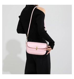 Detail of pink leather shoulder bag with gold metal clasp and chain strap on model