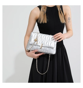 Detail of silver quilted chain bag with gold metallic ball and sleek lock mechanism