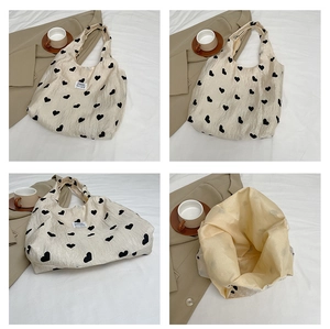 Detail of cream tote bag with black heart patterns and spacious interior compartment