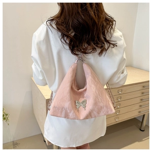 Pink glossy crinkled hobo bag with silver butterfly charm and chain strap shown on model