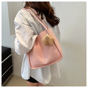 Détail d'un cabas rose avec coutures fines et un charmant petit ours brun en peluche