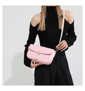 Detail of pink PU leather crossbody bag with gold twist lock on female model