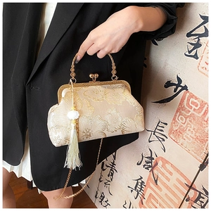 Close-up of vintage beige silk handbag with golden floral embroidery and tassels