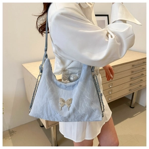 Close-up of light blue pleated PU leather bag with silver butterfly buckle and chain strap