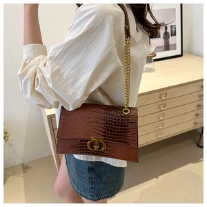 Borsa a tracolla marrone coccodrillo con catena dorata indossata su outfit casual