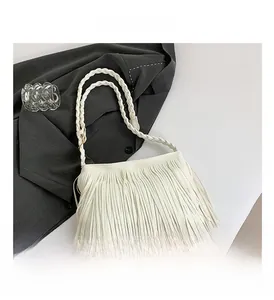 Detail shot of white fringe shoulder bag with braided strap on grey blazer background