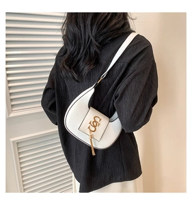 Detail of white crescent shoulder bag with golden logo and tassel on model back