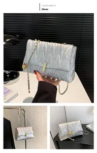 Detail of silver quilted chain bag featuring V-shaped stitching and gold metal turn-lock