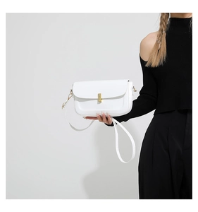 Detailed side view of white minimalist chain shoulder bag with gold metal clasp on model