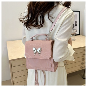 Detail of pink pleated faux leather backpack with metal butterfly and adjustable strap