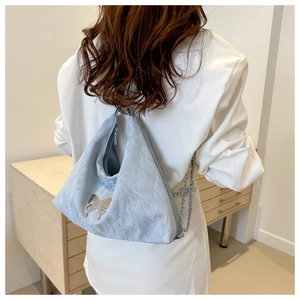 Détail du sac hobo bleu clair avec breloque papillon argentée et bandoulière chaîne