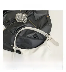 Detail der weißen matten Ledertasche mit breitem verstellbarem Ösenriemen und Metallschnalle