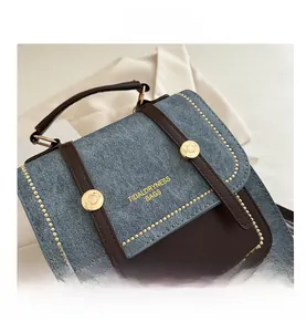 Close-up of retro color-block handbag with blue denim fabric and brown leather detailing