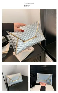 Detail of silver envelope clutch with embossed geometric texture and gold metallic trim