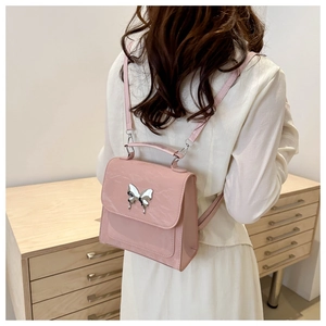 Détail du petit sac à dos rose avec boucle papillon argentée et cuir texturé brillant