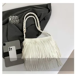 Detailed close-up showing fine tassel fringes and braided strap on beige shoulder bag