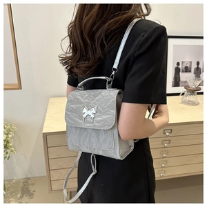 Silver mini backpack with textured leather and a silver butterfly buckle shown in use