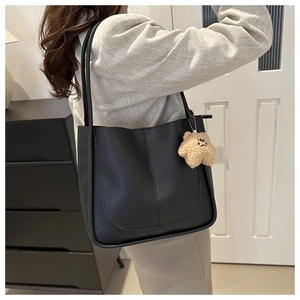 Détail du sac cabas en cuir PU noir avec coutures en U et breloque ours en peluche