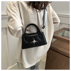 Dettaglio mini borsa a tracolla in pelle nera con ornamento a stella d'argento su modella