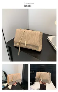 Detail of khaki quilted shoulder bag with golden chain strap and metallic lock closure