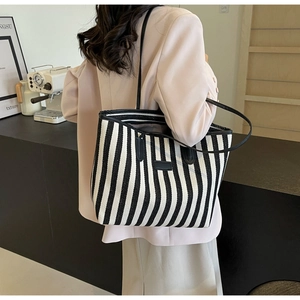 Grand sac cabas à rayures noires et blanches avec anses en cuir porté par un mannequin