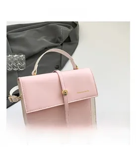 Detail of pink and white crossbody bag with gold rotary lock and embossed text