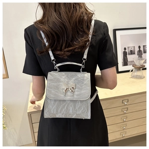 Detail of silver pleated texture backpack with a decorative metallic butterfly clasp