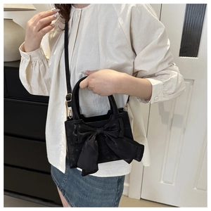 Modella che indossa una borsa a mano nera con un grande fiocco e tracolla elegante