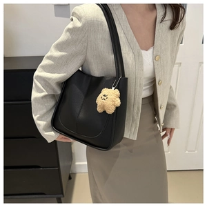 Détail d'un sac cabas noir minimaliste avec un charmant pendentif en forme d'ours