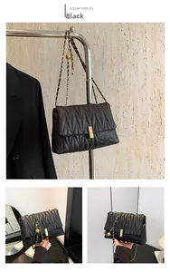 Close-up of black quilted shoulder bag with gold chain strap and wave stitching detail